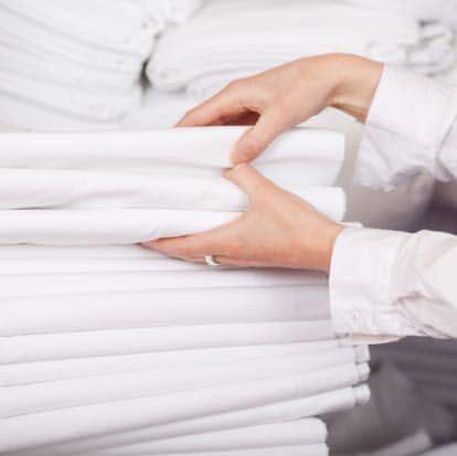 ABC-blanchisserie-grand-est (1) Closeup of white bedsheets stacked in store room of hotel